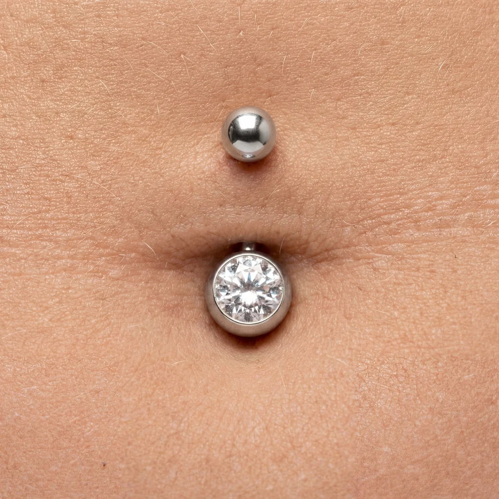 Silbernes Bauchnabelpiercing mit klarem Kristallstein auf Haut in Nahaufnahme