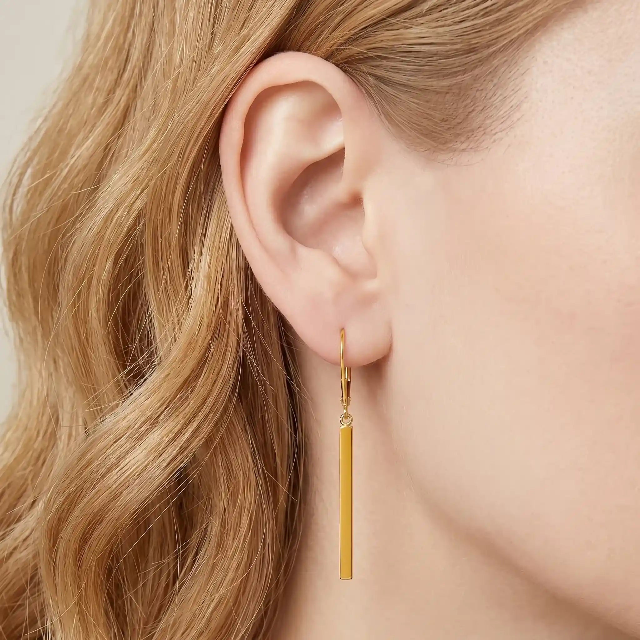 Goldener langer Stab-Ohrring am Ohr getragen, minimalistisches Schmuckdesign