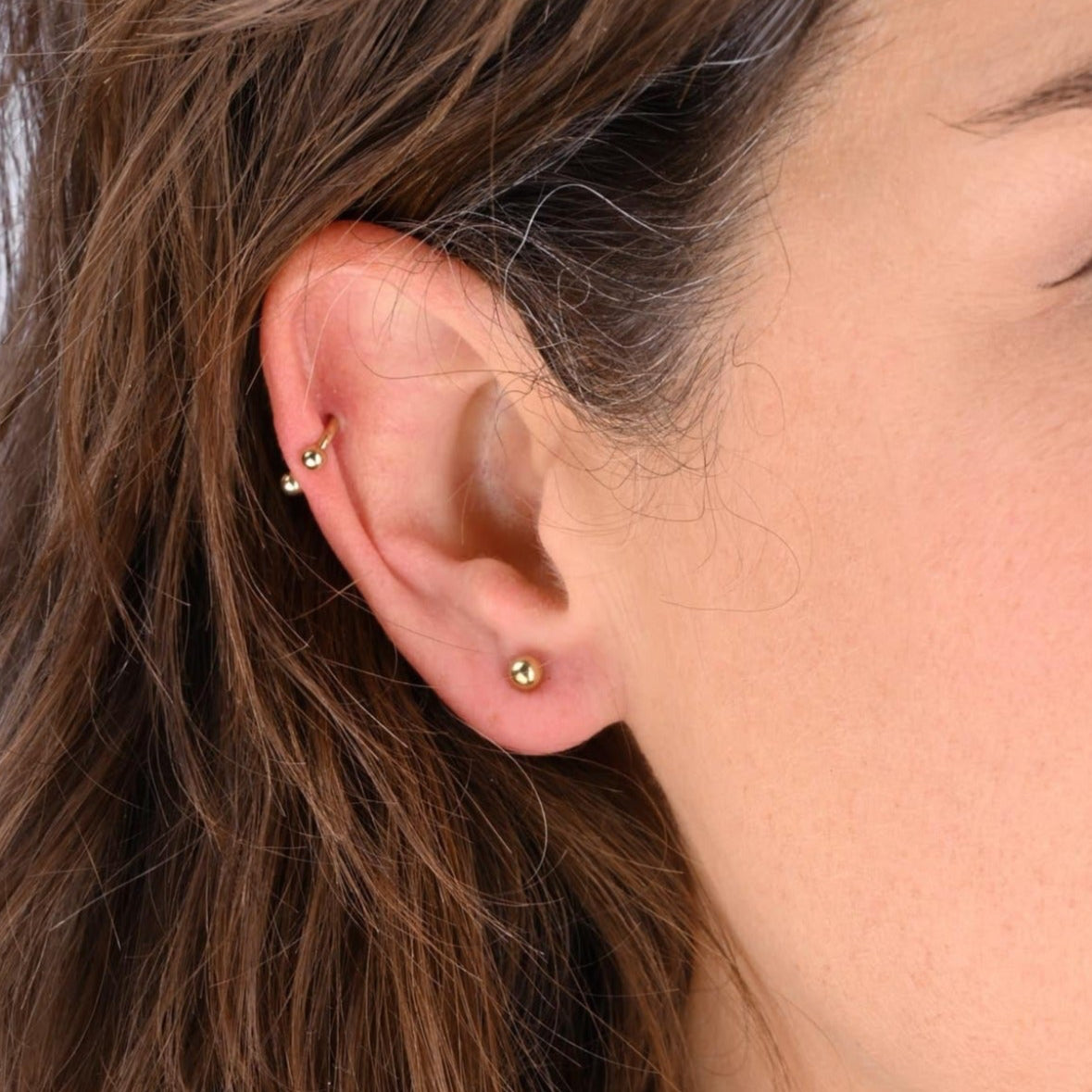 Weibliches Model mit Micro Labret mit Kugel und Hufeisen aus Titan in Gold - Profilansicht